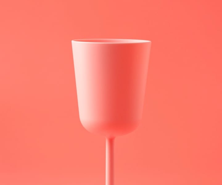 A tall, peach-colored glass in front of a peach background